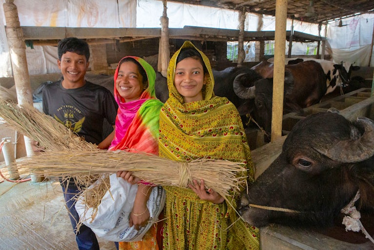 Rebeka and her two children stand beside their buffalo.