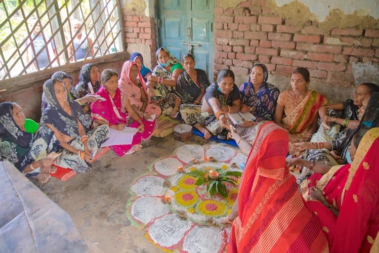 Group of women dressed in cultural attire and sitting in a circle.