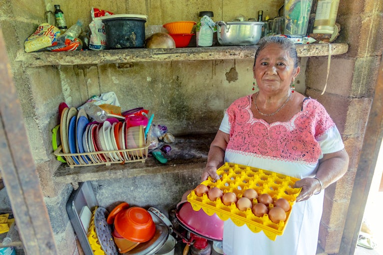 A woman holds a tray of eggs.