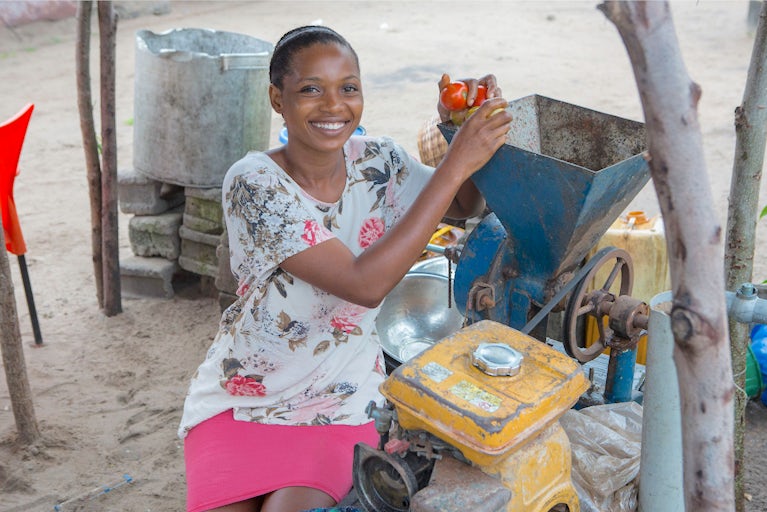 Rofiat Ibrahim, 27, feeds tomatoes into a grinder on June 20, 2023 in Badagry local government area, Nigeria.
