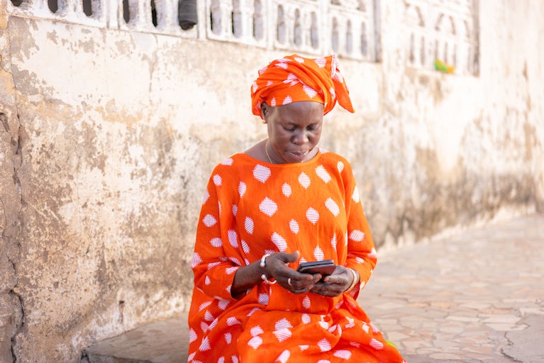 A woman in Senegal checks a weather alert on her phone.