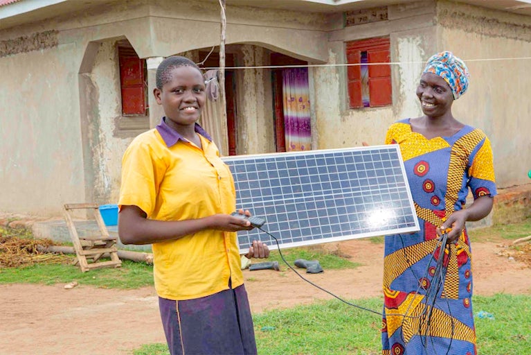 Acico Flavia, 15, and Sarah Akello, 31, hold a solar panel donated from Heifer International in Aduudyek village, Uganda.