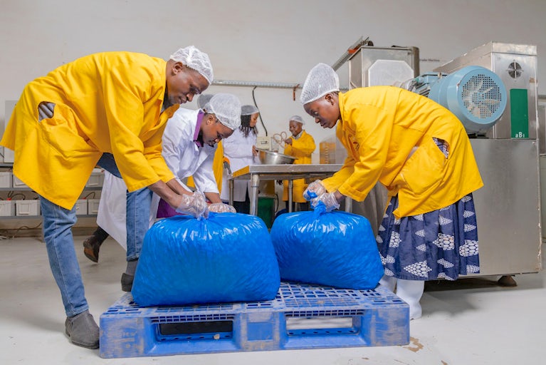 Workers package porridge materials in a processing facility in Uganda.