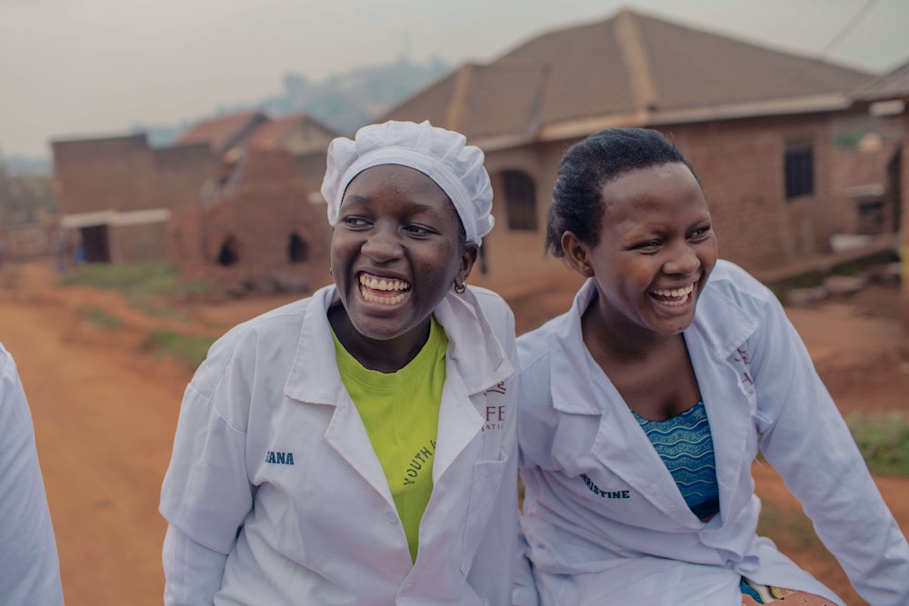 Two women laugh as they travel down a rural road.